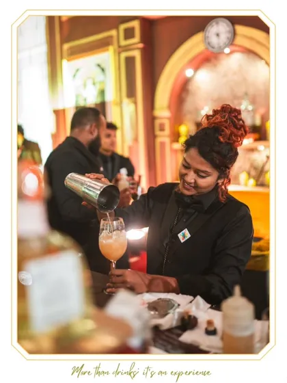 A smile makes every cocktail taste better. One of our talented female mixologists pours a freshly shaken drink, demonstrating the friendly and professional service we are known for.