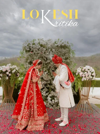 Lokesh and Kritika during their Varmala ceremony, set against a beautiful floral arch and a dramatic sky, creating a truly epic wedding photograph.