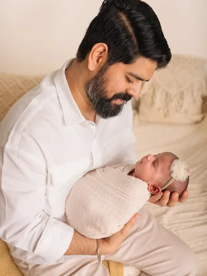 A father gazes lovingly at his newborn daughter. The connection between them is so clear and beautiful in this simple portrait.