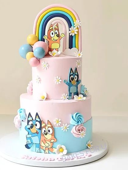 A cheerful two-tier Bluey-themed cake, perfect for fans of the popular show. It features Bluey and Bingo, along with a bright rainbow and daisy decorations, bringing the playful world of Bluey to the party.