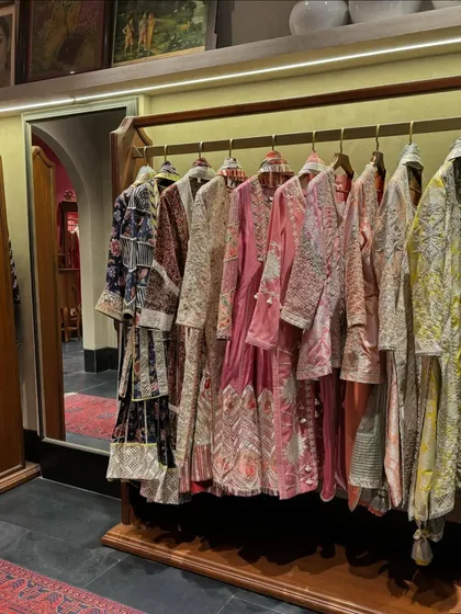Casually dropping some couture. A rack of stunning Anamika Khanna outfits, known for their unique drapes and modern-bohemian vibe.