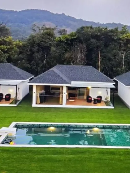 A view of the modern villas and private pool at Panorama Peaks, Coorg, set against a backdrop of forested mountains.