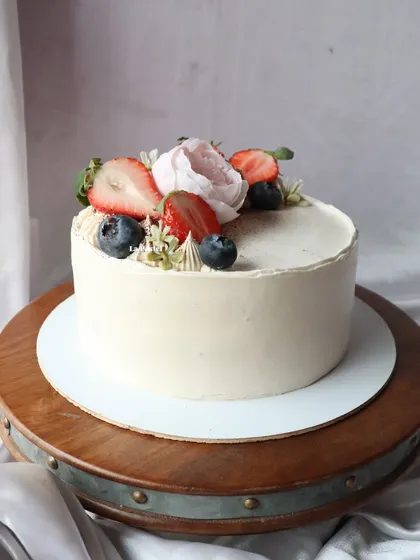 You can't go wrong with fresh berries. This simple and delicious cake is topped with fresh strawberries, blueberries, and a delicate sugar flower, perfect for any occasion.