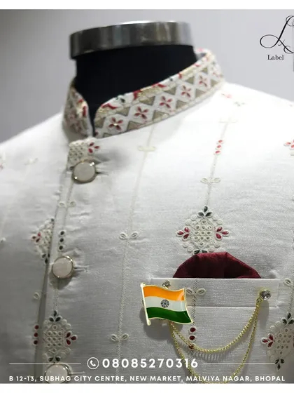 Details matter. This is a close-up of the fine embroidery and unique button work on one of my custom white Bandis. The fabric has a subtle texture, and the collar features a contrasting pattern, showing the thought that goes into every element.
