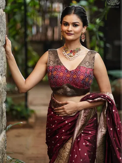 This image shows how a multi-colored stone necklace can bring an entire look together. The model pairs the vibrant choker with a rich maroon saree, creating a harmonious and elegant ensemble perfect for a wedding or celebration. The necklace features a variety of stones, offering versatility to match many outfits.
