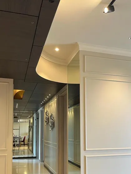 Luxury is in the details. Here, a gracefully curved ceiling detail meets classic wall paneling and mirrored surfaces, creating a sophisticated corridor that plays with light and reflection.