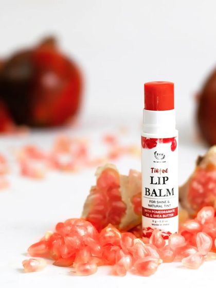 Fresh pomegranate seeds are used as a natural prop to highlight the key ingredient of this tinted lip balm. This fresh, vibrant styling makes the product feel natural and appealing.