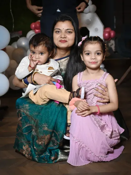 A mother sits with her two children, a toddler and a young girl, holding them close. This portrait showcases the warmth and love of a mother for her kids.