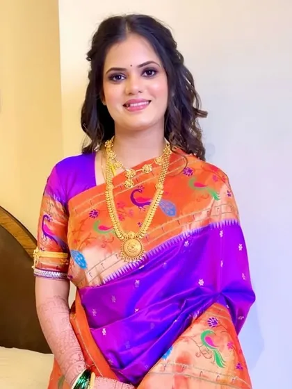 A sophisticated reception look featuring a purple smokey eye that beautifully complements the bride's Paithani saree. The soft curls add a touch of modern elegance.