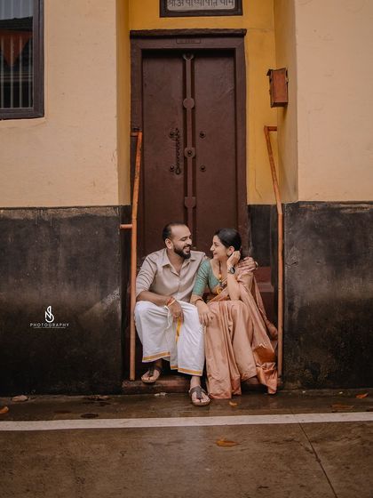 A wider shot of the couple on the steps, showing more of the charming, rustic architecture.