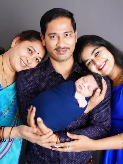 A beautiful three-generation family portrait, with a grandmother, father, and mother lovingly holding their new baby.