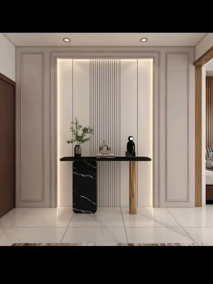 The entryway to a living room, featuring a sleek console table with a black marble base and a gold-finished leg. The backlit wall panel adds warmth and creates a welcoming first impression.