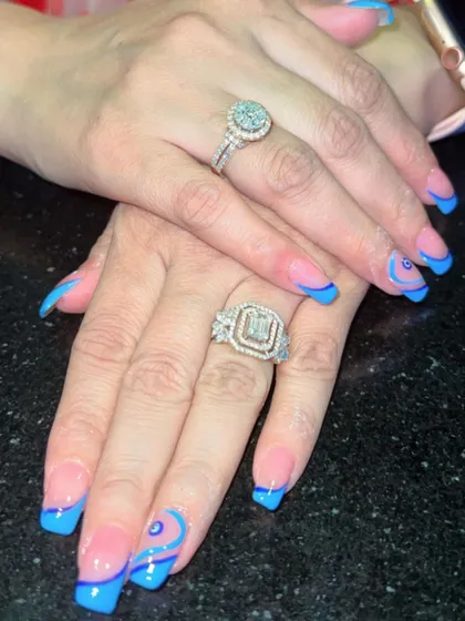 Modern, chic, and a little mystical. This design features a sharp blue French tip on a natural base, accented with a delicate evil eye and swirl art for a trendy and personalized style.