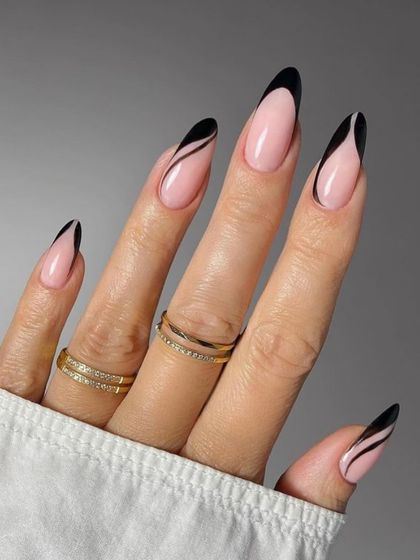 A sleek and modern design featuring a nude base with sharp, black abstract lines and tips on long almond nails.