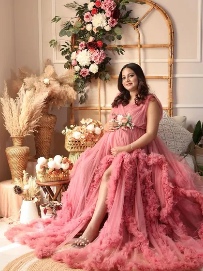 A beautiful solo portrait in a pink ruffled gown, seated gracefully in the boho setup. The soft colors and textures create a dreamy feel.
