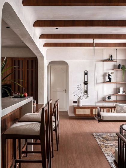 The 'Amoda' home in Pune by The Canvas Project features a warm and inviting interior with an indoor swing, a breakfast bar, and exposed wooden ceiling beams.
