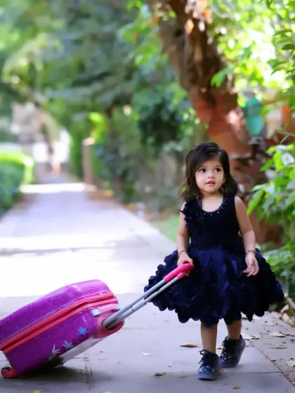 Ready for an adventure! This outdoor shot with a little girl pulling a suitcase is a creative way to capture a sense of wonder and exploration.