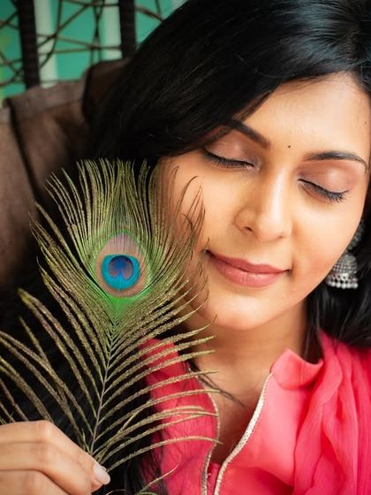 A peaceful and serene portrait, with a peacock feather gently touching her face. This creative shot evokes a sense of calm and connection to nature.