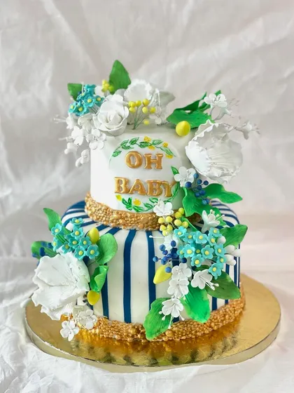 Oh Baby! A stunning two-tiered baby shower cake with a chic blue and white striped design, accented with gold and a burst of beautiful sugar flowers.
