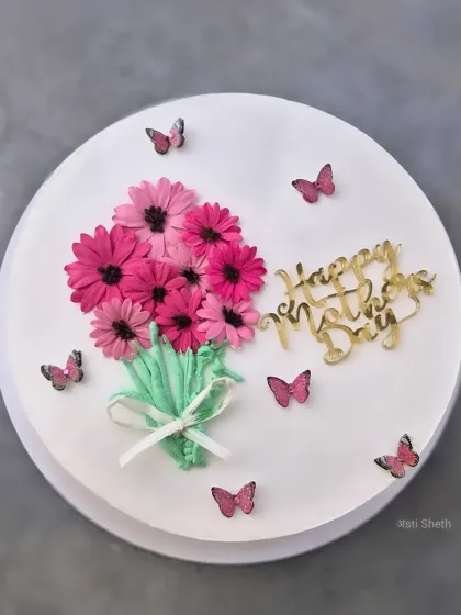 A beautiful Mother's Day cake designed to look like a bouquet of flowers, with piped whipped cream daisies and butterfly accents.