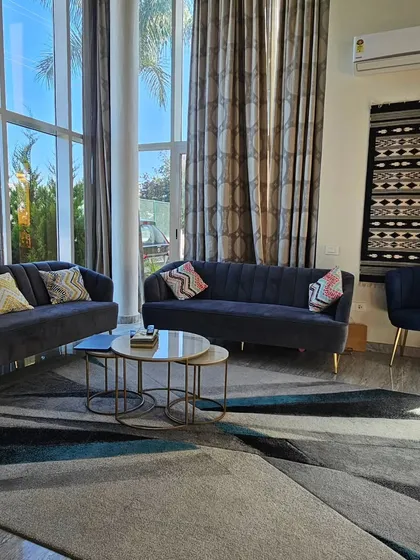 This is a completed living room in a Bangalore villa. The double-height windows bring in ample natural light, and I've used a combination of comfortable sofas and accent chairs to create a welcoming space for the family.