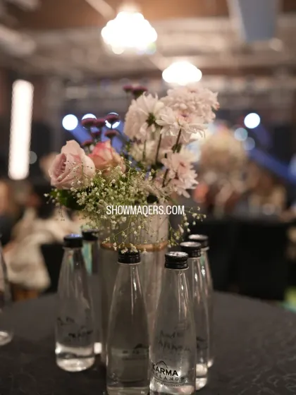 A close-up of a table centerpiece with pink and white flowers, with the main stage visible in the background.