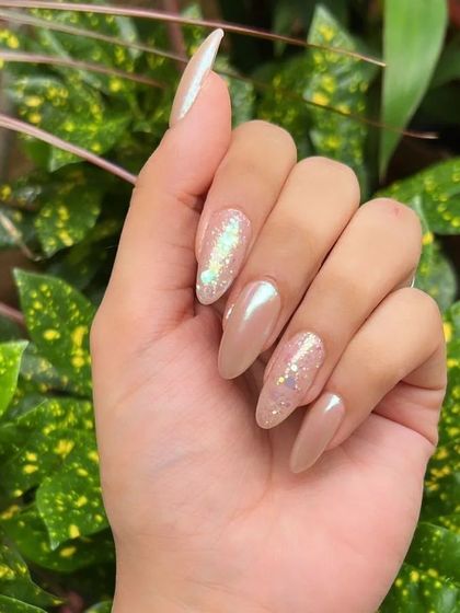 A chic and stylish manicure combining solid nude-pink nails with accent nails featuring a flaky glitter gradient for a touch of sparkle.