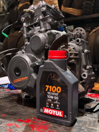 An RC 390 engine on the bench for a piston ring and valve replacement, with a bottle of Motul 7100 oil ready to go.