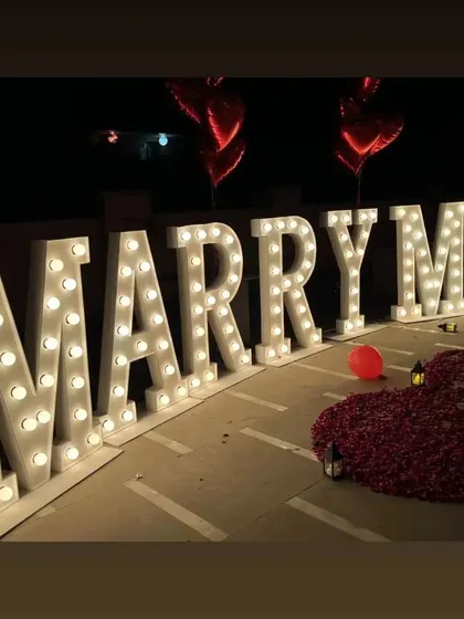 A side view showcasing the scale of our 'MARRY ME' marquee letters. These bright, illuminated letters are a popular choice for evening and nighttime proposals, ensuring a picture-perfect moment.