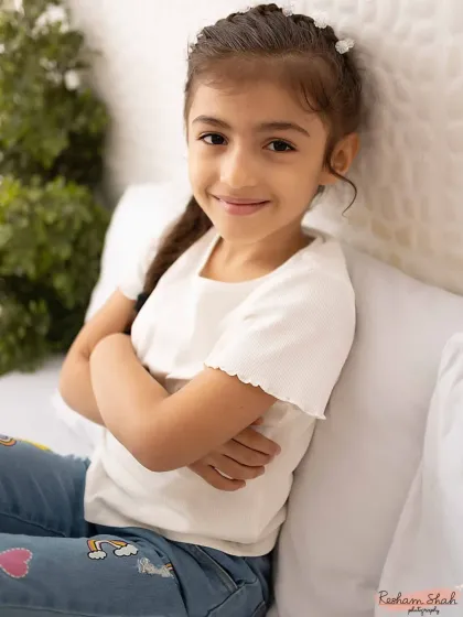 A confident and sweet pose. This close-up portrait captures her gentle expression and the little details, like the patches on her jeans.