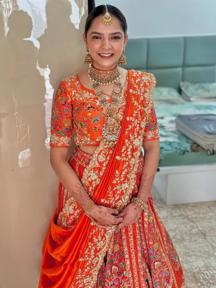 A full view of the happy bride, ready for her big day. The elegant bun complements her intricate jewelry and stunning outfit perfectly.