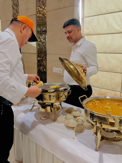 Guests being served from our elegant brass food warmers. We ensure the catering setup is both beautiful and functional.