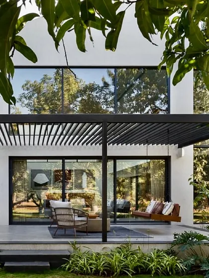 We design spaces that extend living into the outdoors. This covered terrace, featuring a slatted pergola that creates a beautiful play of light and shadow, provides a seamless transition from the living room to the garden, perfect for relaxation and entertaining.