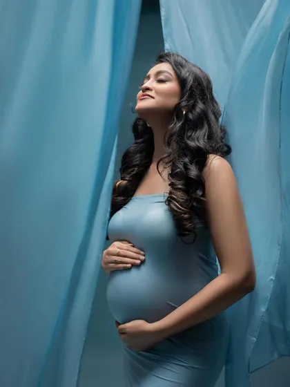 A moment of pure bliss. With eyes closed and a gentle smile, this mother-to-be is completely immersed in the joy of her pregnancy journey.