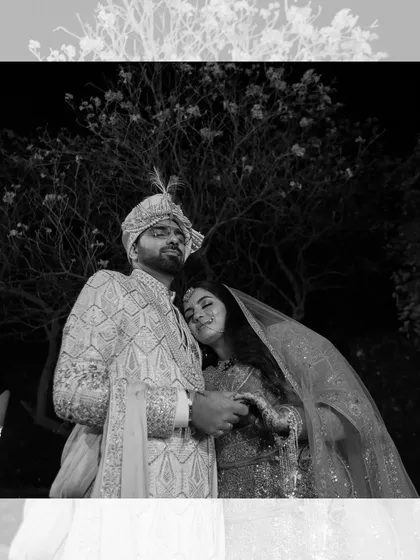 A tender black and white portrait of the newlywed couple. The bride rests her head on the groom's shoulder, capturing a moment of peace and love amidst the celebrations.