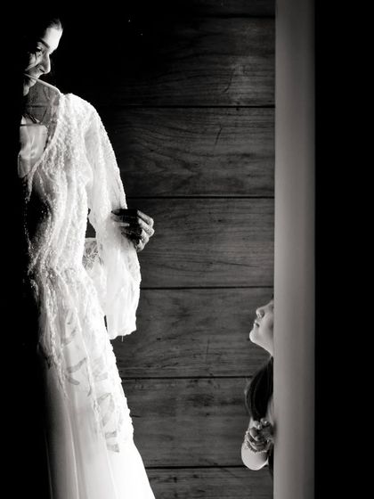 A beautiful, high-contrast black and white shot of a little girl looking up at the bride. A moment of admiration and wonder.