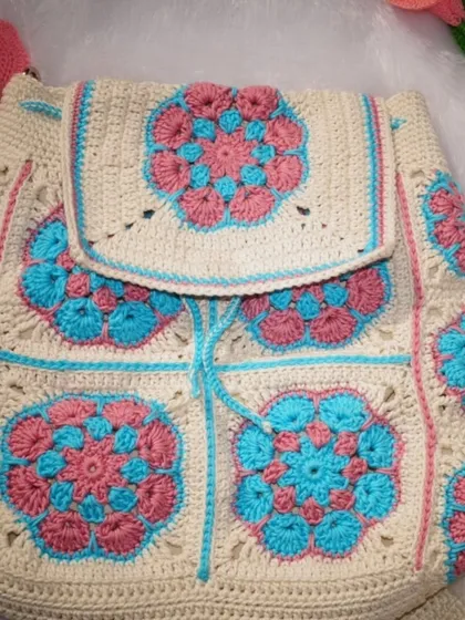 The front view of the backpack, showcasing the flap closure and the beautiful arrangement of the floral granny squares.