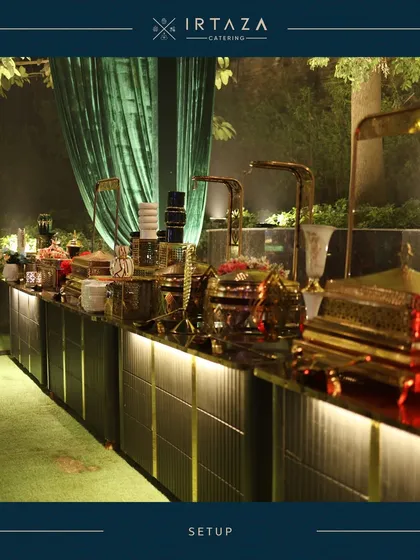 Another view of a grand outdoor buffet. The combination of lush green lawn, elegant green draping, and my signature golden serveware creates a stunning visual for any large-scale celebration.