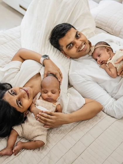 A happy family of four relaxing on the bed. This at-home lifestyle shot with twins is full of joy and natural connection, capturing a perfect family moment.