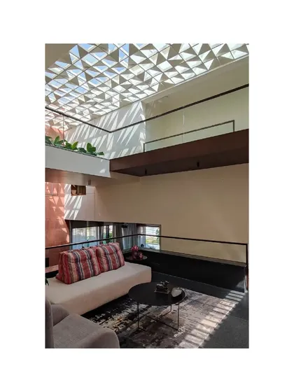 Light filters through a geometric patterned ceiling in the Notan Home, casting dynamic shadows. This is a key example of how I use architectural elements to actively shape the light within a space.