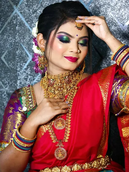 The bride adjusting her maang tikka, a classic pose that highlights the beautiful details of her forehead jewelry and eye makeup.
