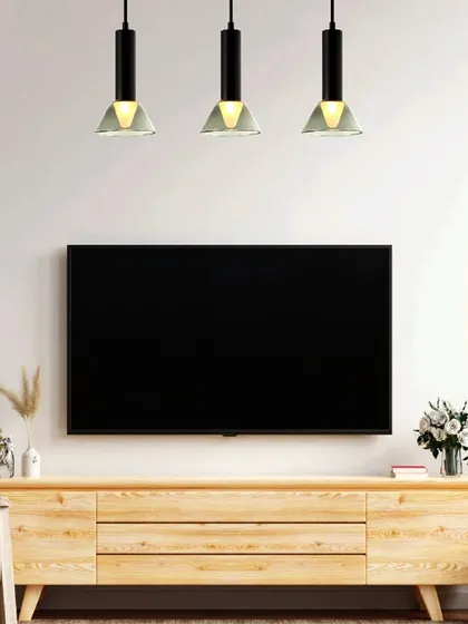 A trio of modern industrial-style pendants hangs over a media console. This linear arrangement provides excellent task lighting while bringing a new dawn of artful, luxury lighting to the space.
