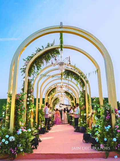 A beautiful floral archway that feels like a painting. This entrance tunnel, with its repeating golden arches and lush pink and white flowers, is one of my signature designs for a romantic wedding.