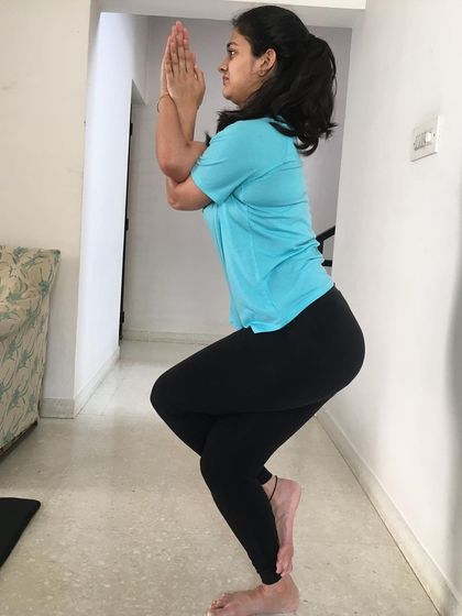 A student holds Garudasana (Eagle Pose), a balancing posture that stretches the hips, thighs, and shoulders while improving focus.