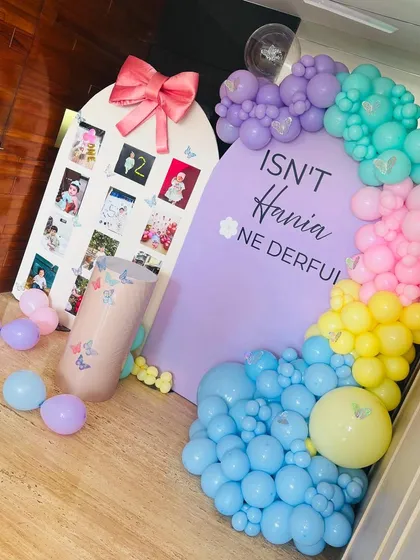 A "Onederful" first birthday for Hania. This setup uses a pastel rainbow of balloons and a custom arch that doubles as a photo board to display pictures from her first year.