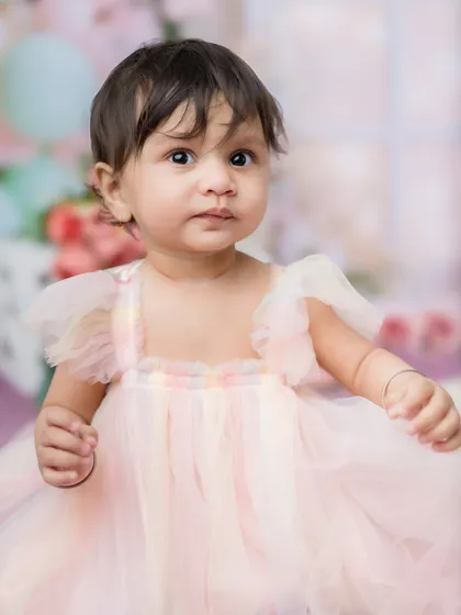 A close-up portrait showing the delicate details of her dress and her sweet, curious expression.