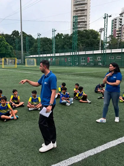 A sports psychologist from our partner Mpower Minds gives a talk to our young players, who are seated on the pitch. This session is part of our holistic approach to player development.