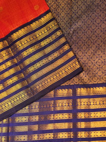 A detailed view of the red and blue Kanjivaram, showing the rich brocade work on the blue pallu and the classic red body.