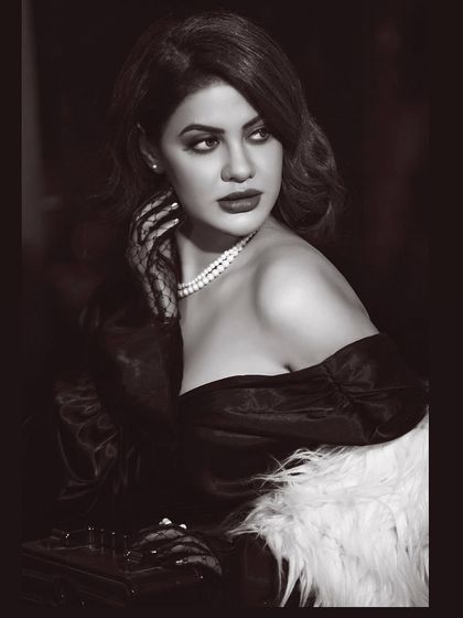 A vintage-inspired black and white portrait. The styling with pearls, lace gloves, and classic Hollywood waves creates a timeless and glamorous old-world movie star look.