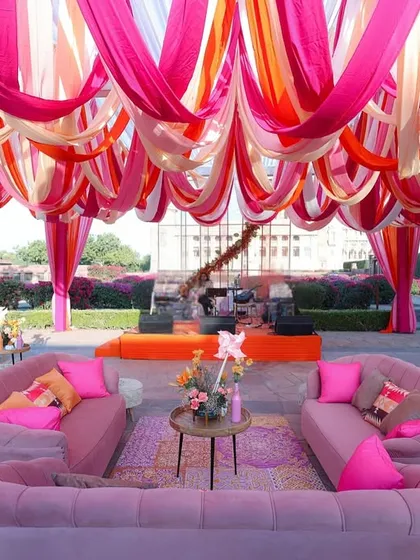 The full lounge setup, with multiple pink sofas and colorful cushions arranged under a canopy of vibrant drapes.